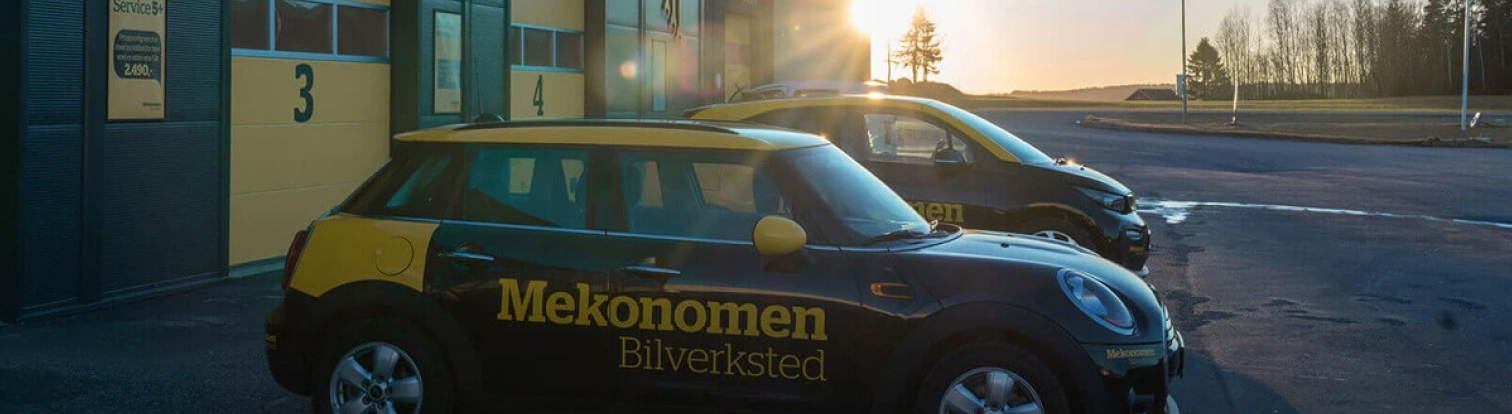 Mekonomen bilverksted og svart og gul Mekonomen bil i solnedgang