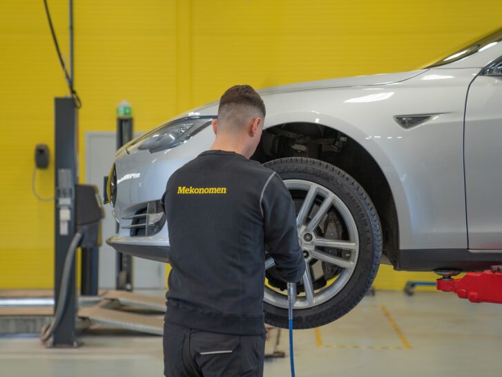 Mekaniker skifter dekk på en bil på et Mekonomen verksted (gul vegg)