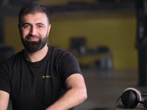 Mekonomen mekaniker med svart t-skjorte, mørkt hår og skjegg