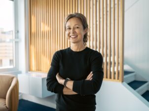 Dame i sort genser foran en spilevegg i eik