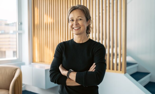 Dame i sort genser foran en spilevegg i eik