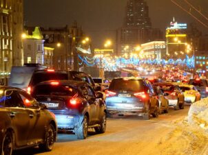 Stor trafikk og julerush i by en førjulskveld med snø på bakken