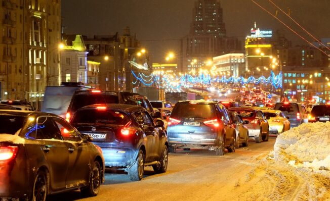 Stor trafikk og julerush i by en førjulskveld med snø på bakken
