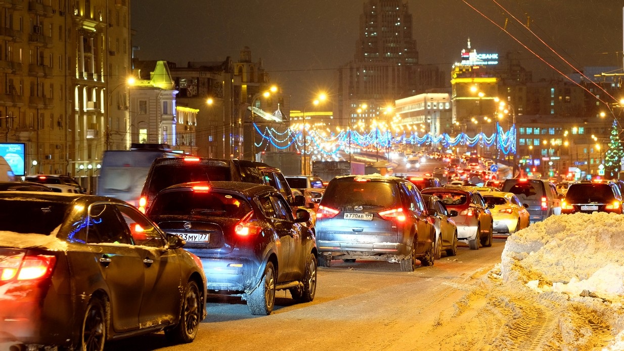 Stor trafikk og julerush i by en førjulskveld med snø på bakken