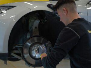 Mekaniker sjekker bremser på hvit bil