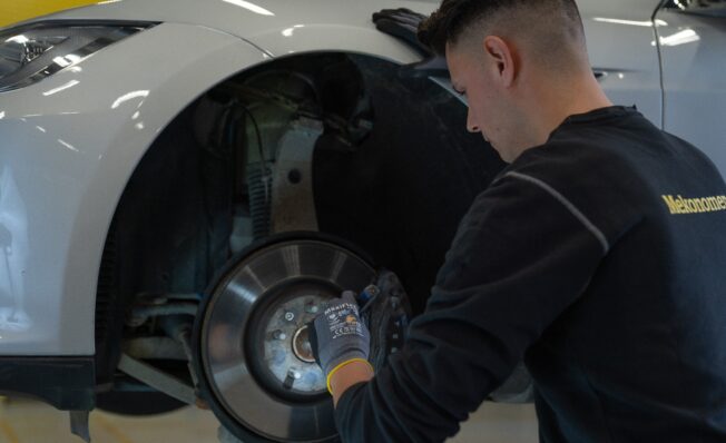 Mekaniker sjekker bremser på hvit bil