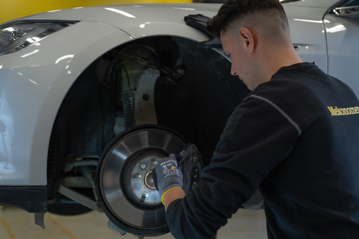 Mekaniker sjekker bremser på hvit bil