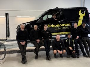 8 mekanikere foran svart Mekonomen bil inne på verkstedet