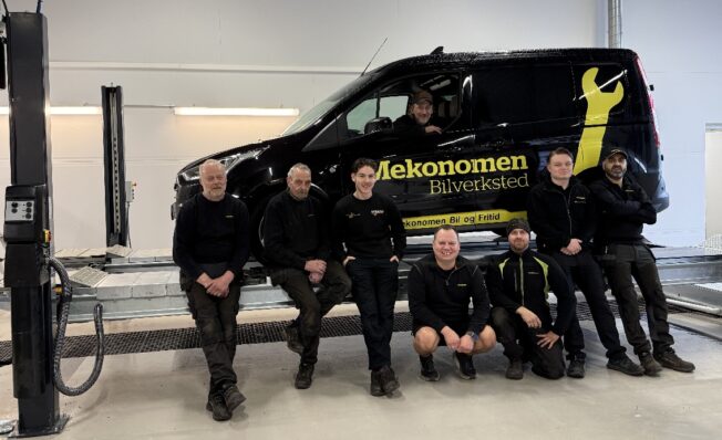 8 mekanikere foran svart Mekonomen bil inne på verkstedet