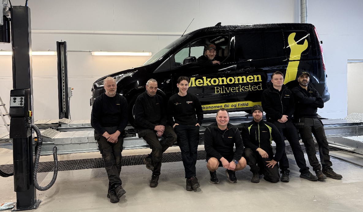 8 mekanikere foran svart Mekonomen bil inne på verkstedet