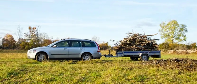 Sølvgrå stasjonsvorgn med tilhenger med kvister på