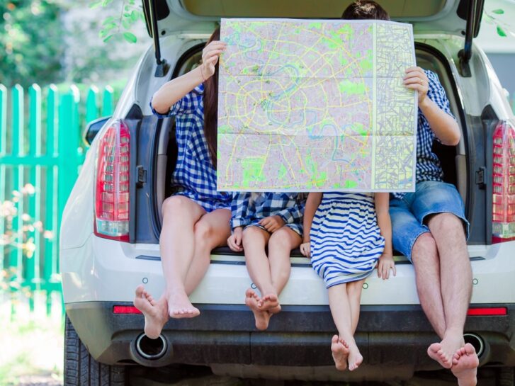 Familie sitter på kanten av bagasjerommet og ser på kart